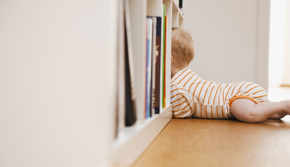 bebelus de-a busilea care se uita in biblioteca