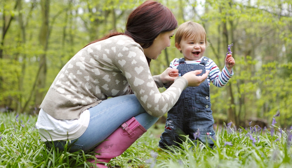 mama si copilul care stau pe iarba in padure