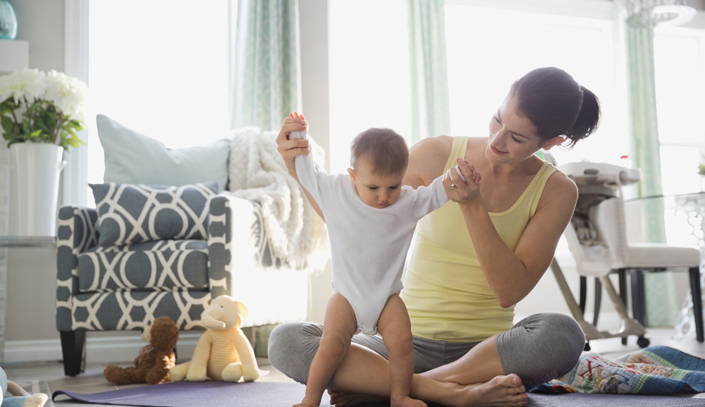 mama care tine de maini bebelusul care invata sa mearga