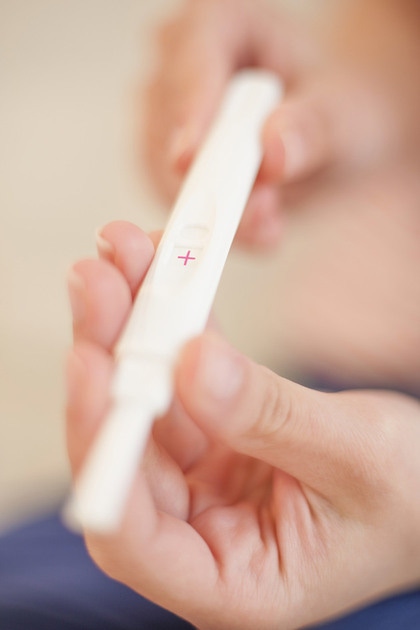 prim plan cu maini de femeie care tin un test de sarcina in mana