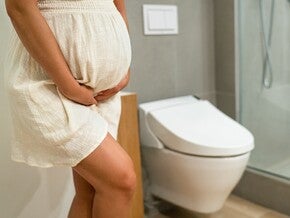 Persoană însărcinată în baie, prezentând simptome digestive frecvente în sarcină.