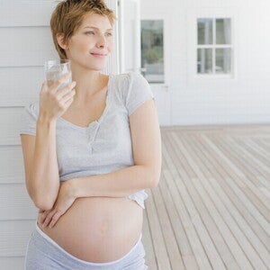 Femeie gravidă cu un pahar cu apă