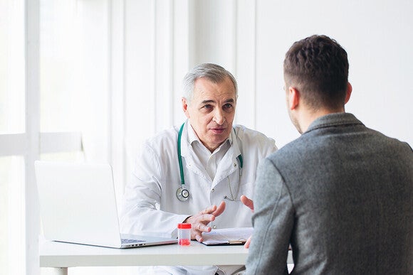 Photo of a doctor with stethoscope consulting a male patient across a desk